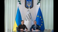 Ukraine's Minister of Health, Viktor Liashko (left) and HI's Ukraine Programme Director, Christian Fuchs (right) sit next to each other and sign a Memorandum of Understanding.