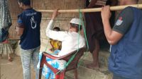 HI volunteers evacuate an elderly person in a chair rigged to a bamboo pole